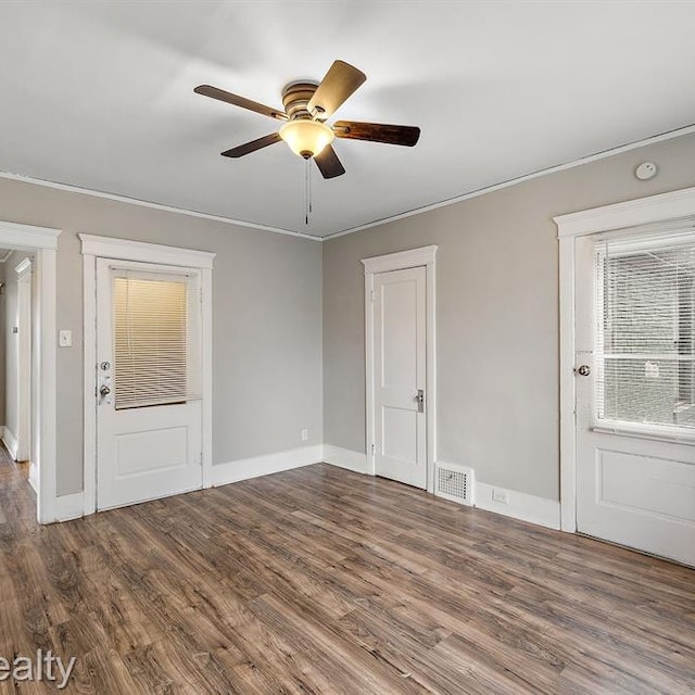 empty room with visible vents, ceiling fan, baseboards, and wood finished floors