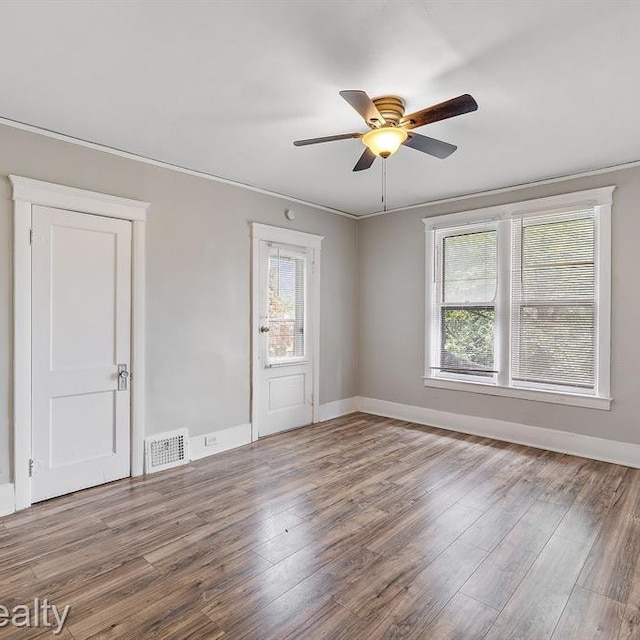 spare room with baseboards, visible vents, ceiling fan, and wood finished floors