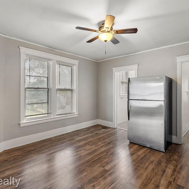 spare room featuring a ceiling fan, baseboards, ornamental molding, and dark wood-type flooring