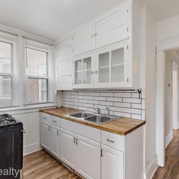 kitchen featuring white cabinets, wooden counters, and a sink