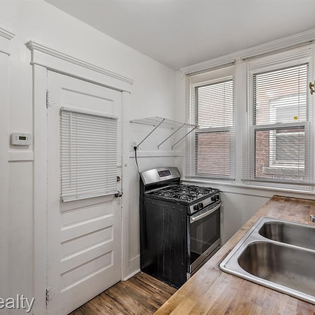 kitchen featuring light countertops, stainless steel gas stove, a sink, and wood finished floors