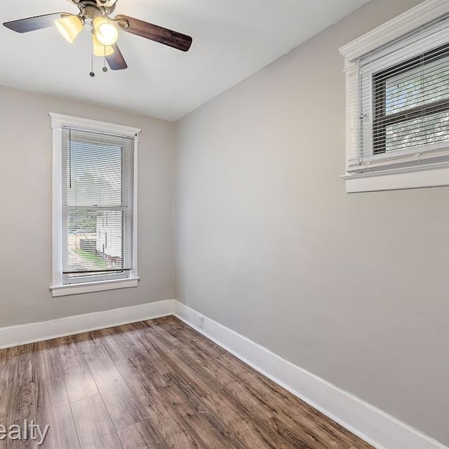 unfurnished room with wood finished floors, a ceiling fan, and baseboards