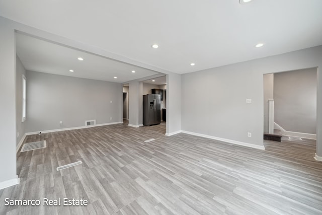 unfurnished living room with recessed lighting, visible vents, baseboards, light wood-style floors, and stairway