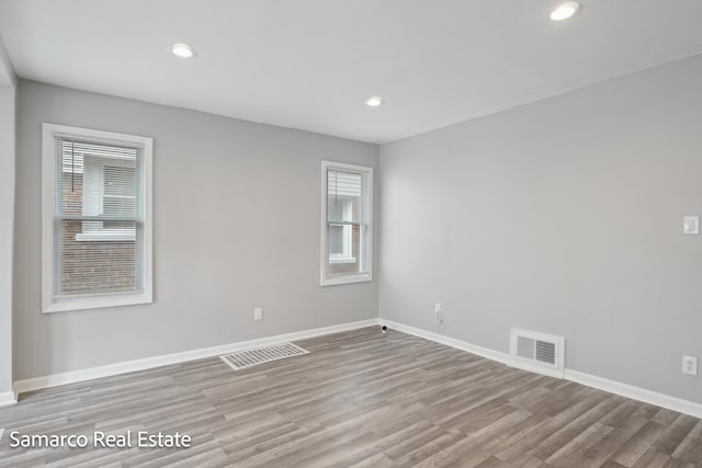 spare room with baseboards, visible vents, and wood finished floors