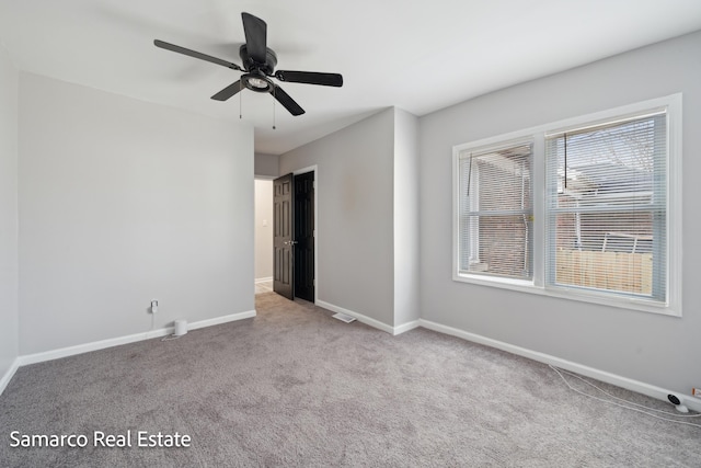 carpeted empty room with a ceiling fan, visible vents, and baseboards