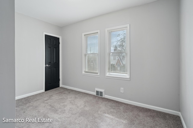 carpeted spare room with visible vents and baseboards