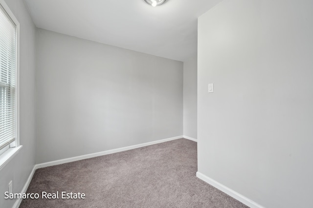 carpeted spare room featuring baseboards