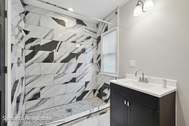 full bath featuring a tile shower and vanity