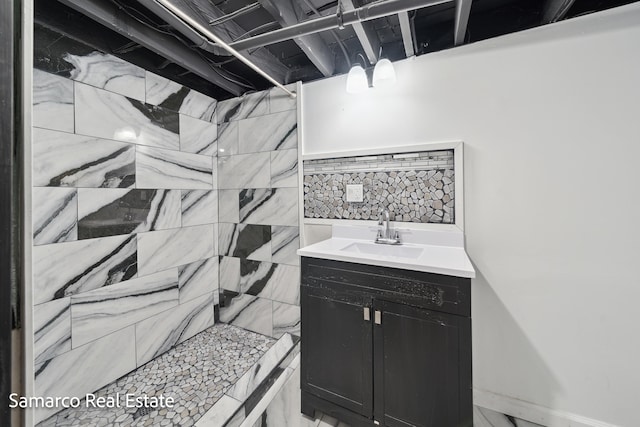 bathroom with a tile shower and vanity