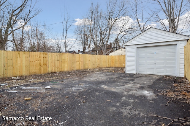 view of yard with fence, aphalt driveway, and an outbuilding