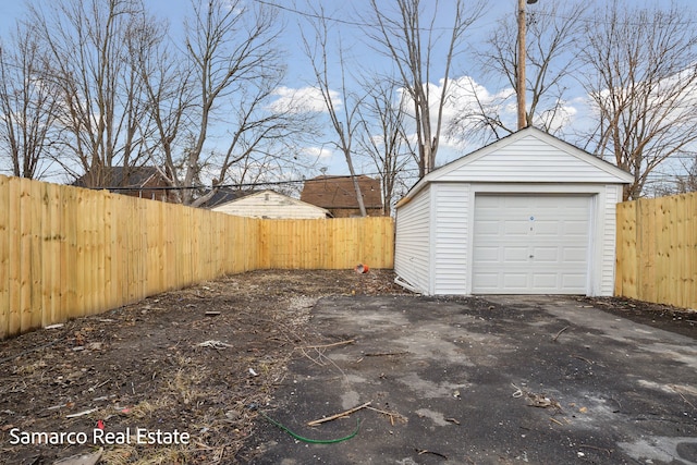 detached garage featuring aphalt driveway and fence