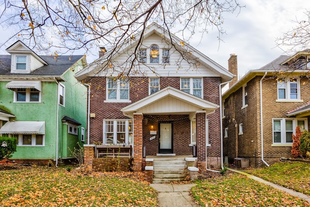 view of front facade with brick siding, a chimney, and central AC unit