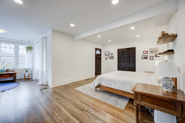 bedroom with beam ceiling, baseboards, wood finished floors, and recessed lighting