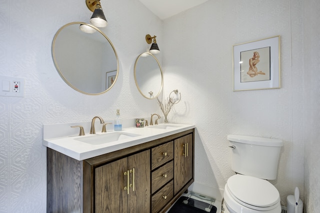 bathroom with toilet, double vanity, and a sink