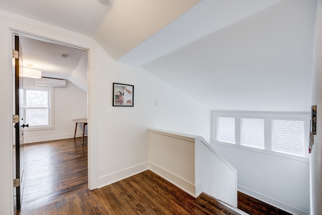 hall featuring dark wood-style floors, baseboards, and an upstairs landing