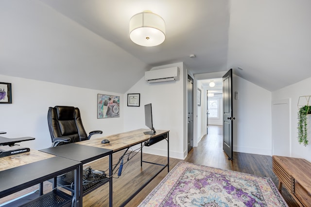 office space with a wall unit AC, baseboards, vaulted ceiling, and wood finished floors