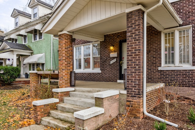 view of exterior entry featuring a porch and brick siding