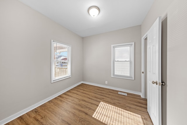 unfurnished bedroom featuring wood finished floors, visible vents, and baseboards