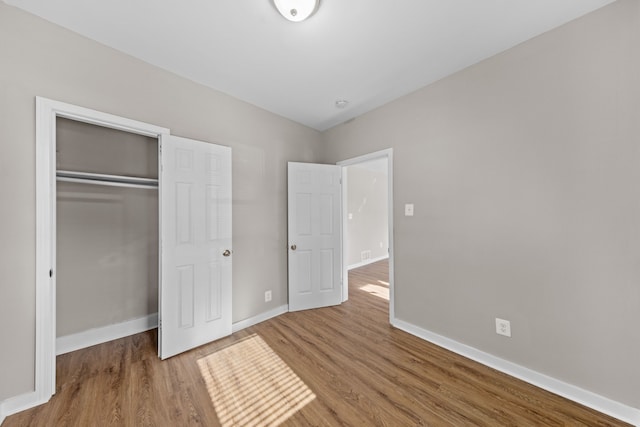 unfurnished bedroom with a closet, baseboards, and wood finished floors