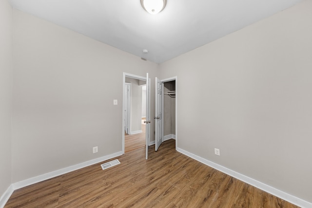 unfurnished bedroom featuring a closet, visible vents, baseboards, and wood finished floors