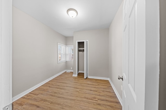 unfurnished bedroom with a closet, light wood-type flooring, and baseboards