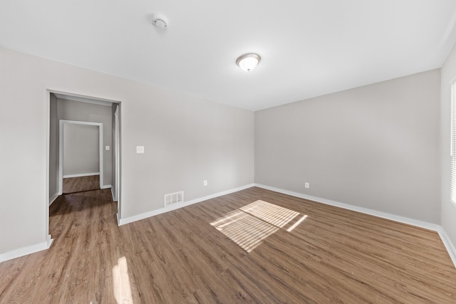 unfurnished room with visible vents, baseboards, and wood finished floors