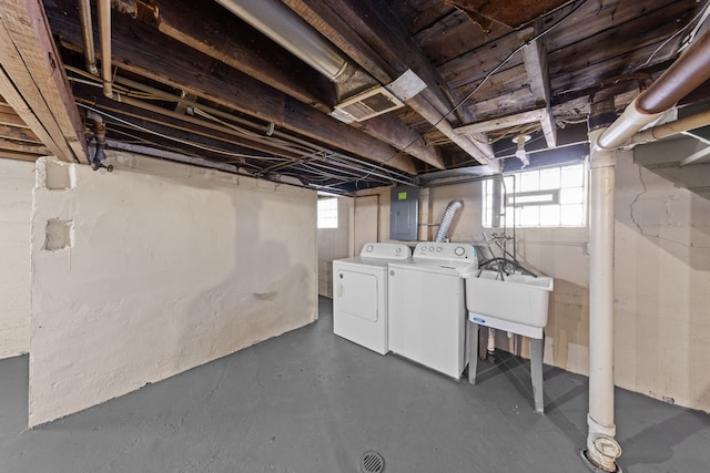 basement with plenty of natural light, a sink, electric panel, and washer and dryer