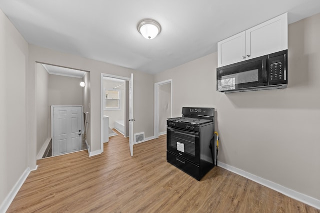 kitchen featuring visible vents, baseboards, white cabinets, light wood-type flooring, and black appliances