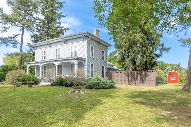 exterior space featuring a porch, an outdoor structure, fence, a chimney, and a front yard