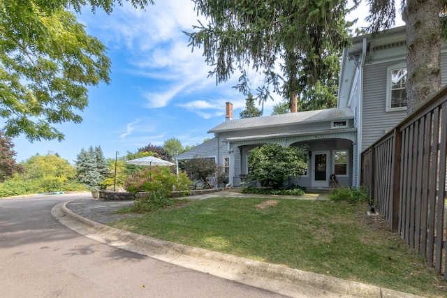 view of front of home with a front yard, fence, and a chimney