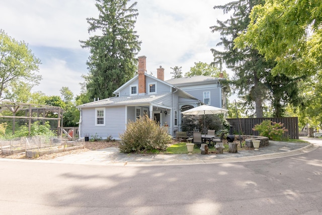 view of front of home featuring a vegetable garden, a chimney, and fence