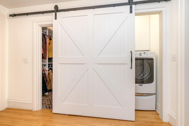 washroom with washer / clothes dryer, baseboards, light wood finished floors, and a barn door