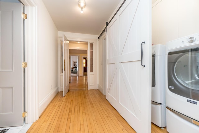 washroom featuring laundry area, a barn door, and light wood-style floors