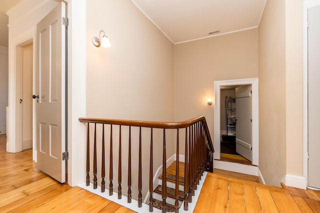 staircase featuring ornamental molding, wood-type flooring, visible vents, and baseboards