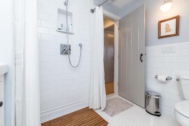 full bath featuring tile patterned flooring, tiled shower, tile walls, and toilet