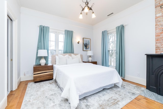 bedroom featuring crown molding, light wood finished floors, baseboards, and a notable chandelier