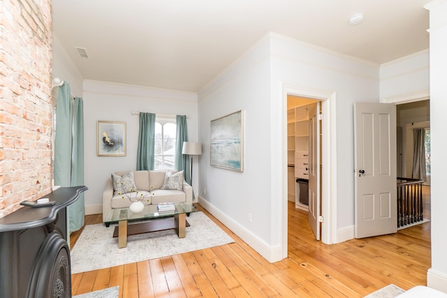 living room featuring light wood-style floors, baseboards, and ornamental molding