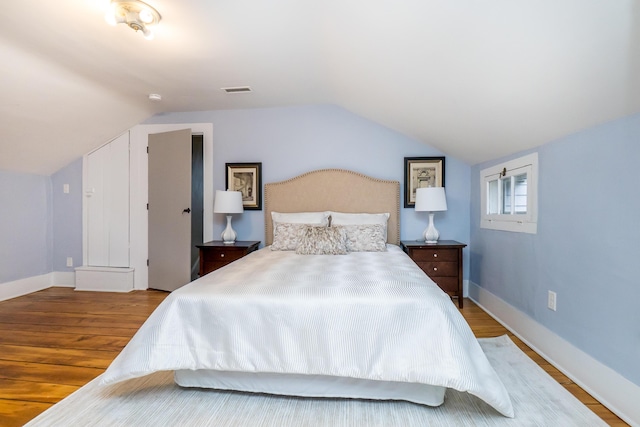 bedroom featuring vaulted ceiling, wood finished floors, and baseboards