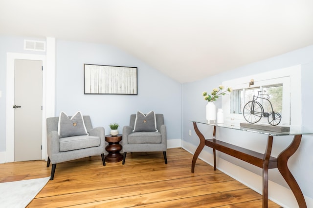 living area with vaulted ceiling, light wood-style flooring, and visible vents