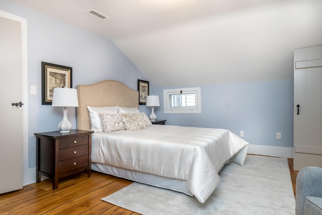 bedroom with vaulted ceiling, wood finished floors, and visible vents