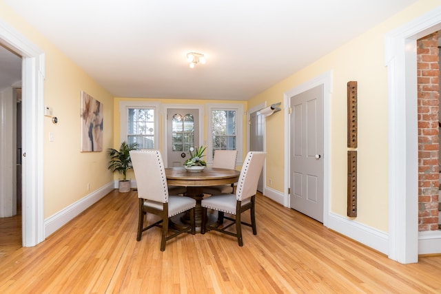 dining space with light wood-type flooring and baseboards