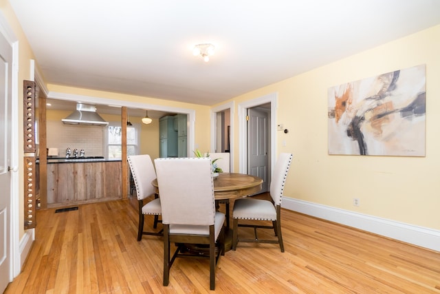 dining room with light wood finished floors, visible vents, and baseboards