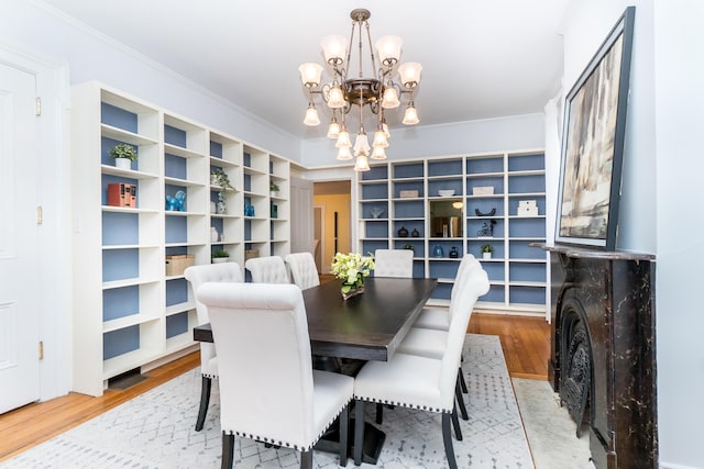 dining room with a notable chandelier, ornamental molding, and wood finished floors