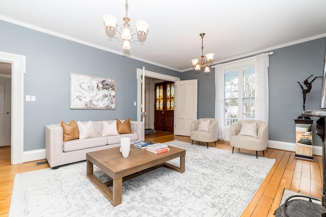 living room with an inviting chandelier, wood-type flooring, ornamental molding, and baseboards