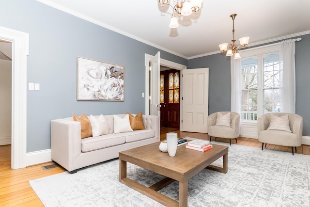 living room featuring a chandelier, wood finished floors, visible vents, baseboards, and ornamental molding