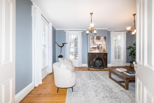 living area with light wood finished floors, crown molding, baseboards, and a notable chandelier