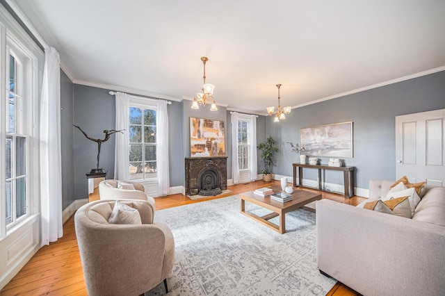 living room featuring ornamental molding, light wood-style flooring, baseboards, and an inviting chandelier