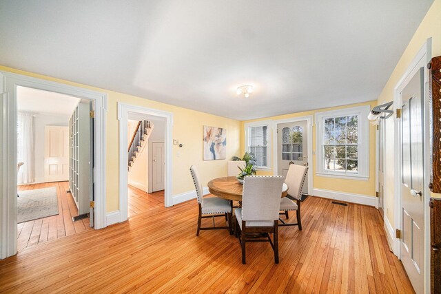 dining room with visible vents, stairs, light wood-style flooring, and baseboards