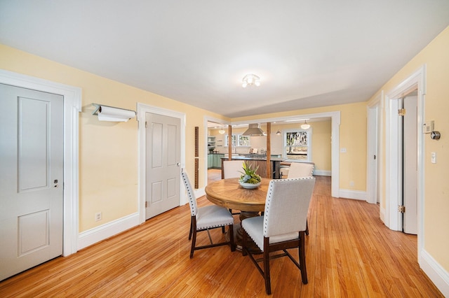 dining space with baseboards and light wood finished floors