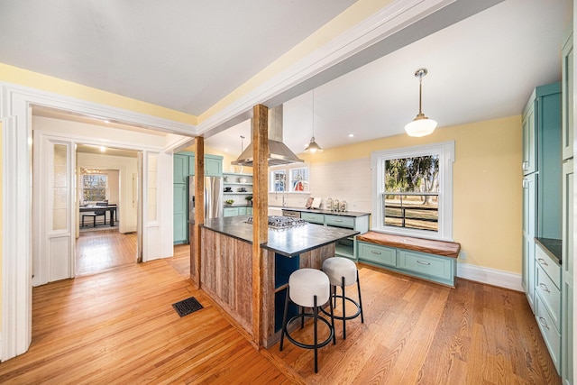 kitchen featuring light wood finished floors, a center island, stainless steel appliances, green cabinets, and exhaust hood